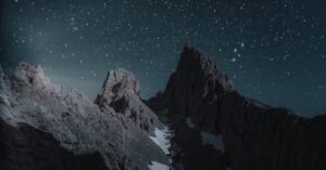 Breathtaking view of a rocky mountain peak under a starry night sky, perfect for wallpapers.