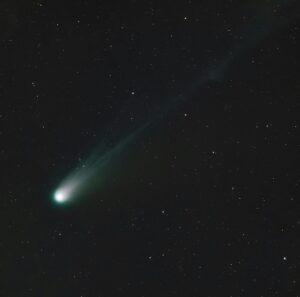 A breathtaking view of a bright comet trailing through the night sky amidst numerous stars.