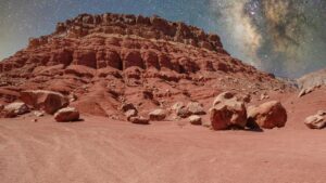 Stunning red rock formations under the Milky Way, resembling a Martian terrain.