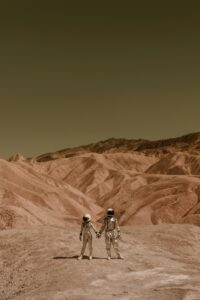 Two astronauts holding hands in a barren, Mars-like desert landscape.